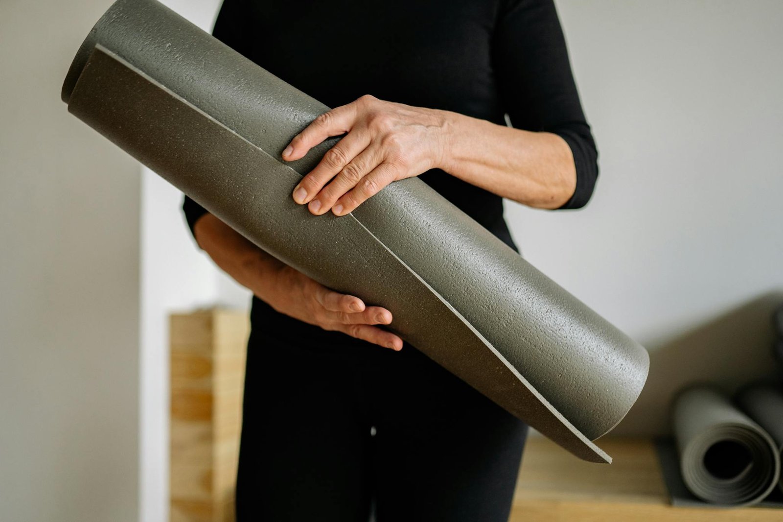Focused shot of hands holding a yoga mat indoors, ready for practice.